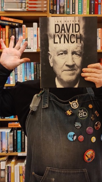Me in our bookshop, holding up a large, coffee table book on David Lynch. The cover is a life-size photo of his face, so I held it directly in front of my own face!