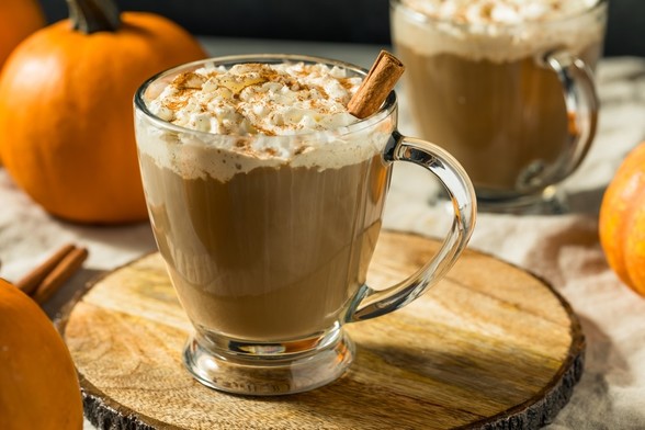 Photo of a clear mug filled with pumpkin-spiced coffee.