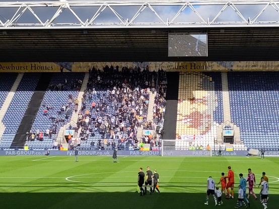 Visiting football fans in the away stand, part of the face of Bill Shankly, a former Preston North End player can be seen in the coloured seats.