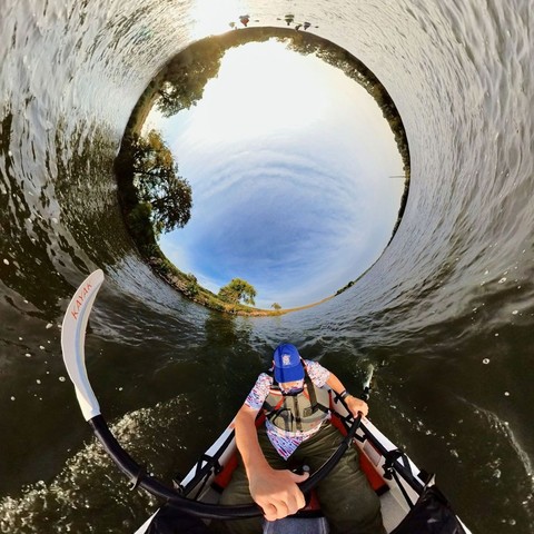 Photo of a person kayaking on a lake under blue skies.