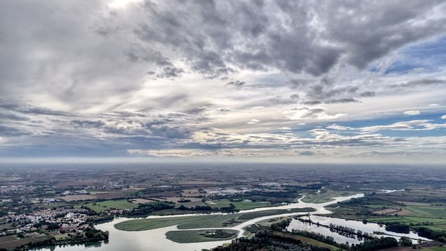 Aerial photo in an overcasted sky of a river opening in marshes and a lake.