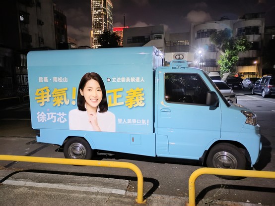 A small light blue delivery van with a photo and slogan to promote KMT candidate Hsu Chiao-hsin