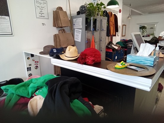 a row of hats on a counter, a bin of hoodies in front of the counter