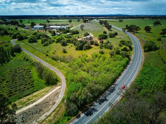 A birdseye view of a road curve around right lower corner of the photo 
So much green around in Knowsley Victoria Australia
