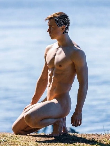 A college age, smooth bodied, naked Terminator freshly transported on the beach has the back part of its skull removed