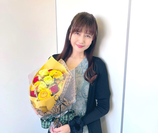 Kikuko holding a brouqet of flowers while smiling.