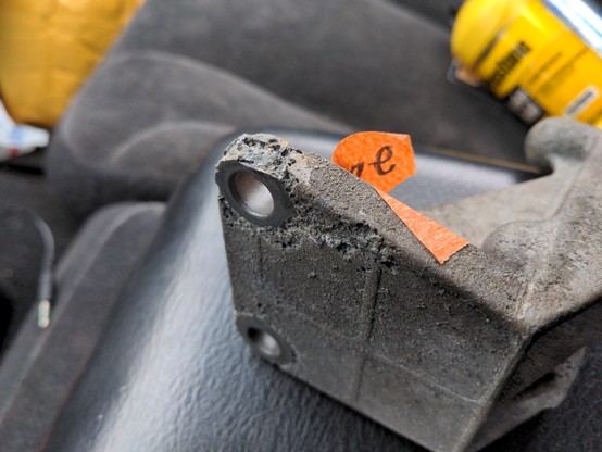A used aluminum bracket showing serious signs of decay. The metal is flaking away and almost porous. The damage is consistent with acid damage (likely murietic acid used to remove oil and grease).