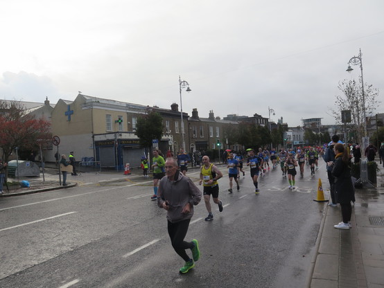 People running along a city street in athletics gear. The sky looks grey.