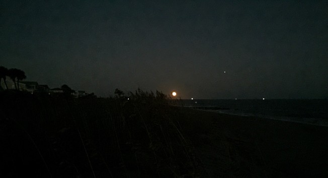 Color image of the moon rising over the Atlantic Ocean in Coastal Carolina, following Jupiter's own rise. The other lights are the LED lights on shrimp boats out for the night's haul