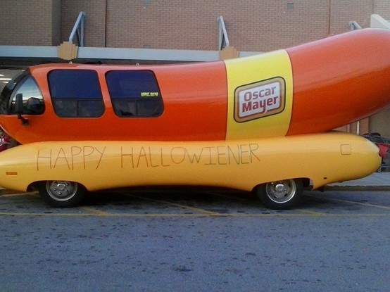 The Oscar Mayer Wienermobile (a retro vehicle that looks like a hot dog in a bun) is all dressed up for Halloween! 

Someone has written "Happy Hallowiener!" on its side.