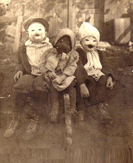 A set of vintage black & white photos of children wearing homemade Halloween costumes. They are very disturbing images, to put it mildly. 

Three kids wearing dirty clothes and boots have whole-head masks on that, honestly, look like real pig's heads.