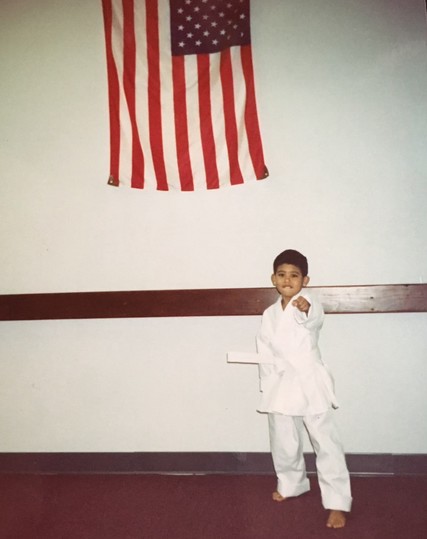 5 year old me in my tae kwon do outfit next to an American flag