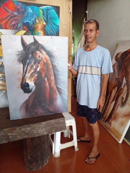 a photo of my friend A, holding up a painting of a horse's head