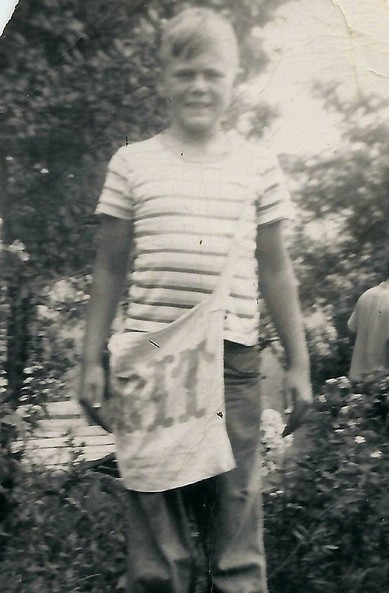 Picture of boy with a newspaper canvas bag over his shoulder Rit in black and white.