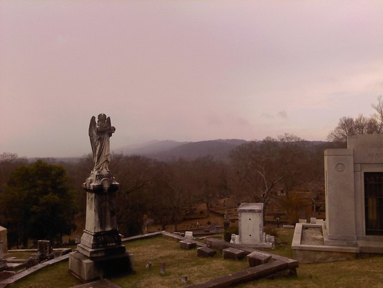 Color image of cemetery in Rome, Georgia. The cemetery is located on a number of hills, and the highest is crowned with a crypt and an angel.