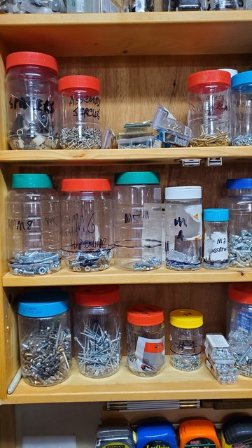 Workshop shelves full of hand labeled plastic jars full of screws and hardware.