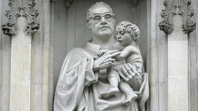 Stone sculpture of a bespectacled man holding a child: Archbishop Oscar Romero from El Salvador, assassinated in 1980. The modern carvings unveiled in 1998 stand in 15th century niches, the pillars ornamented with crockets and lively animal heads.