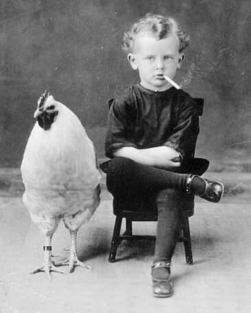 A boy and his chicken. The boy is smoking a cigarette.