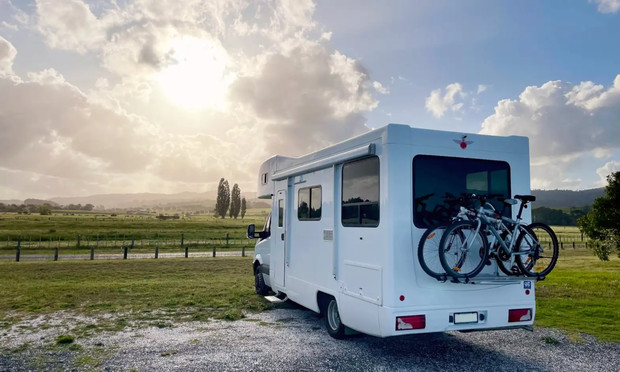 Motorhome seen from rear, with bikes on back, pointed towards sunset