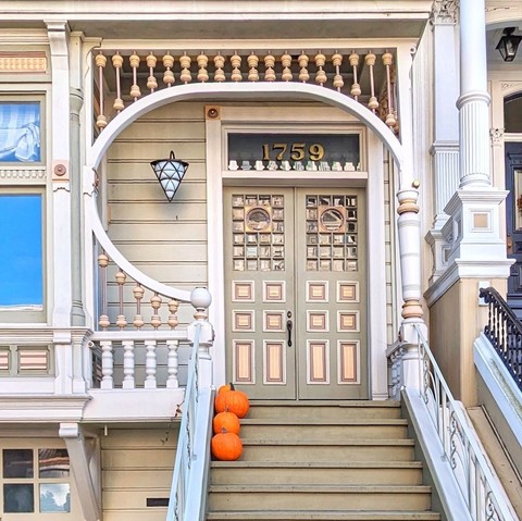 Beige Victorian door with a conical lamp and pumpkins in front on the stairs.
