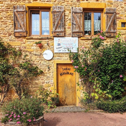 Door on a golden brick building. Caveau Beaujolais is written on the door in curved letters.