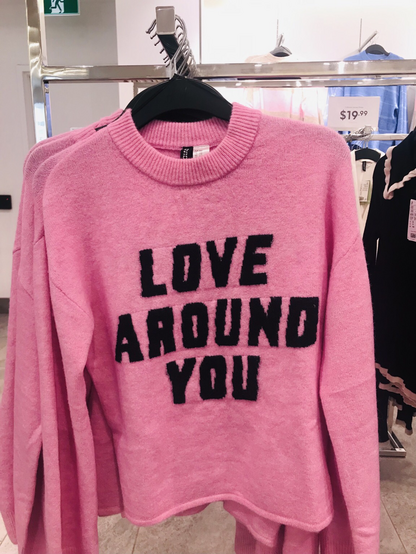 Pink sweater with black text that says “love around you” photo by Crissy@tech.lgbt