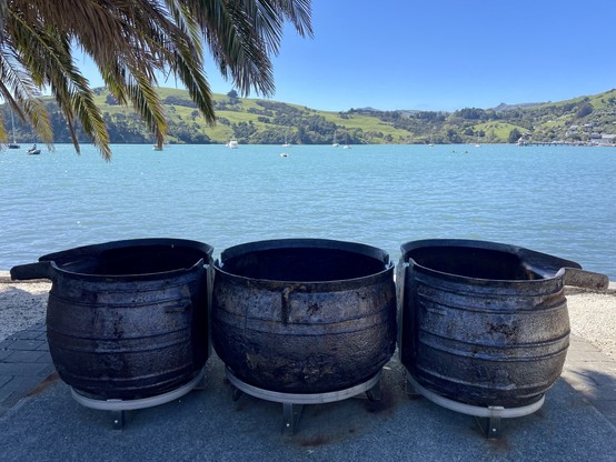 Cast iron pots used in processing whale products, displayed on a pedestrian walkway