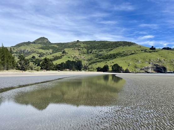 Rugged hills reflected in wet sand of the beach
