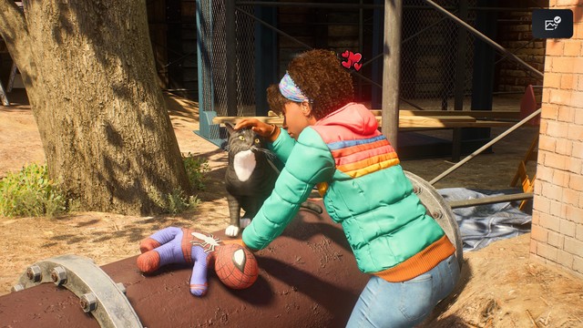 Girl petting a black and white tuxedo cat on a pipe, with a Spiderman plushie cat toy laying nearby, from Spiderman 2.