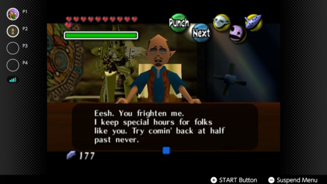 Screenshot from The Legend of Zelda: Majora's Mask being played on the Nintendo Switch. It's showing the Curiosity Shop owner. He says, "Eesh. You frighten me. I keep special hours for folks like you. Try comin' back at half past never." Link tried talking to him while as Zora Link.