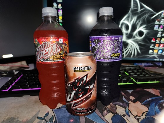 In the foreground are two bottles of Moutain Dew and between those two is a can of Mountain Dew. On the left is the Halo themed flavor Citrus Cherry, in the middle is a Call of Duty Advanced Warfare themed flavor citrus cherry, and on the right is a Diablo 4 themed flavor mystic punch