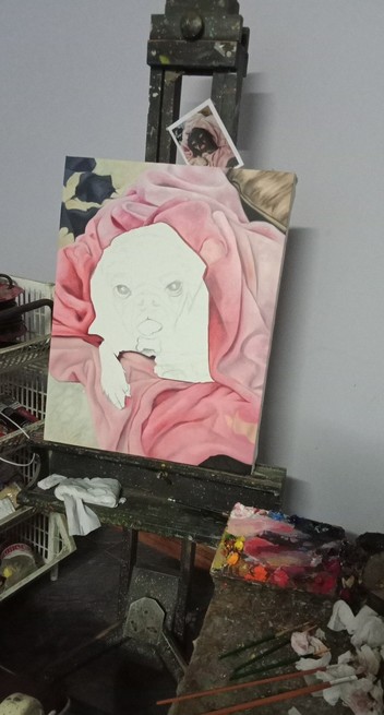 a photo of a painting on an easel, the center part is white with faint graphite guidelines, the pink blanket is painted in, the oil paint is on a small table next to my seat