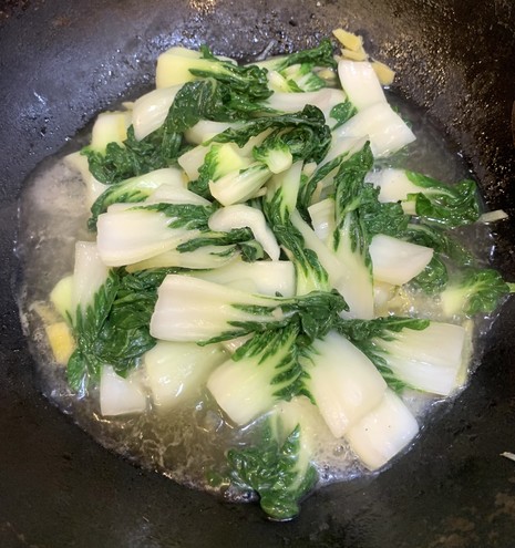 Sizzling sautéed Bok choy with a lot of ginger in a Chinese wok.