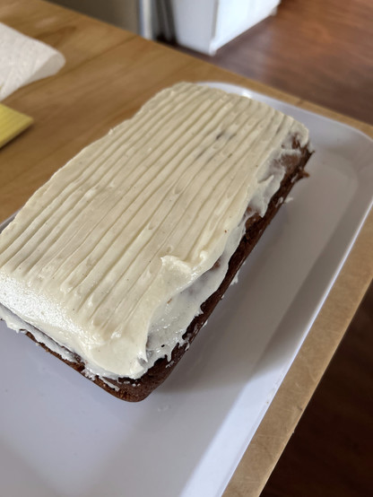 Dark cake with white icing sits on a plate.