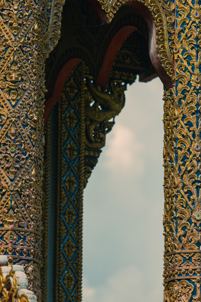 A photo of the late morning sky framed in an intricate gateway to a temple near the old city in Chiangmai