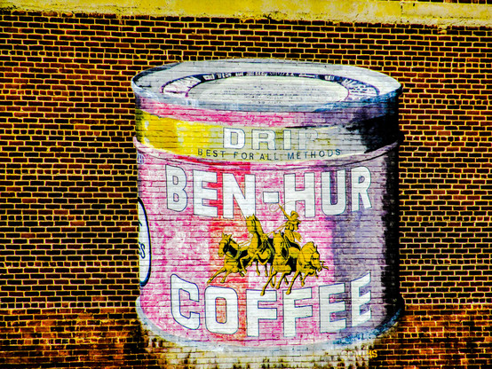 A can of Ben Hur Coffee spray painted on a brick wall