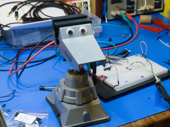 A small metal workbench-top vise sitting in the middle of an electronics work area.  Because of pareidolia, it resembles a face, or possibly a duck's head.

It therefore has had two googly-eyes attached to it, on one jaw of the vise.