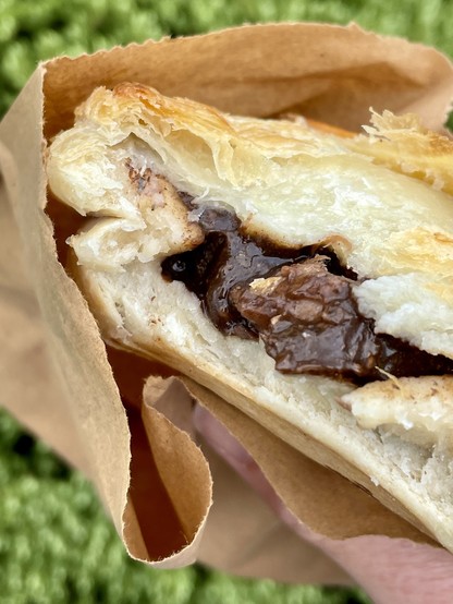 Partially eaten pie in a paper bag showing filling inside pastry