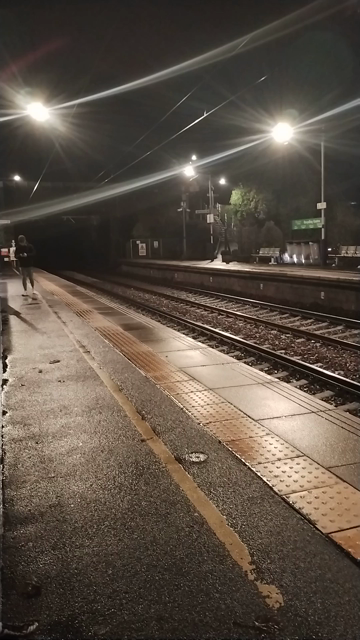 Looking along the night-time railway platform, when a non-stop express hurtles past from behind me