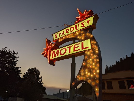 Photo of a neon sign lit up at night. It features a stylized comet and the words STARDUST MOTEL.