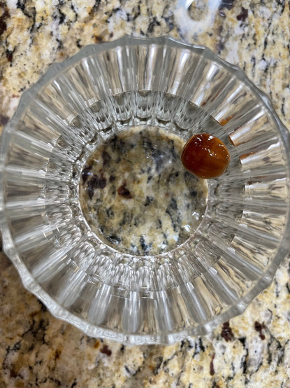 An acorn floating in a tumbler full of water on our kitchen counter. I've named the acorn Junior and if he sinks, he's okay to plant. If he floats, he's not viable.  Unfortunately, Junior is floating.