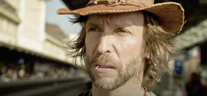 Close-up of the mysterious, roughly-hewn hero, with his weather-beaten cowboy hat and cocktail stick between his teeth. (He is played by Tonton Pierrick.)