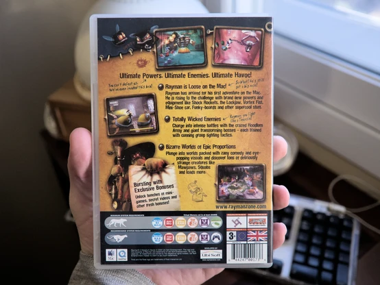 Photo of the back side of the game's DVD box. It has some typical marketing highlights of what you'll find in the game, with the first one talking about how this is the first adventure for Rayman on Mac. There are also a few screenshots shown.