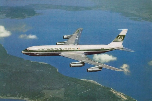 4 engine jetliner over the clouds, water and green lands