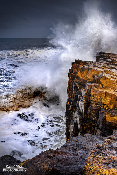 A small rocky promontory on the Northumberland coast pictured with waves crashing.