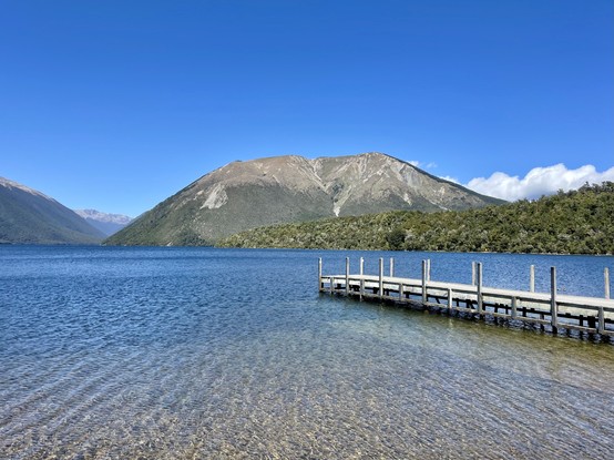 Small wooden jetty juts out into clear Lake; Mount Robert dominates the mid ground; lake extends into distance left of frame