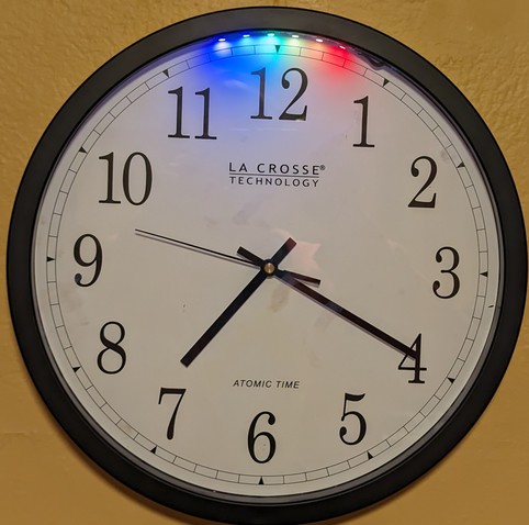 Photo of an analog clock with an array of six RGB LEDs at the top, showing a rainbow pattern