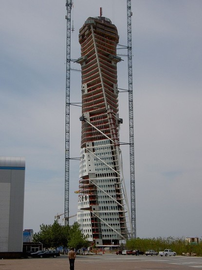 a photo of a tall skyscraper being constructed, it looks like someone took a straight rectangular tall building and twisted it