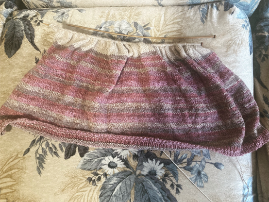 An in progress knitted sweater made of purple and beige yarn