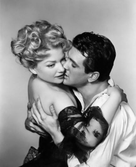 a black and white photograph of Anne Baxter and Rock Hudson embracing passionately